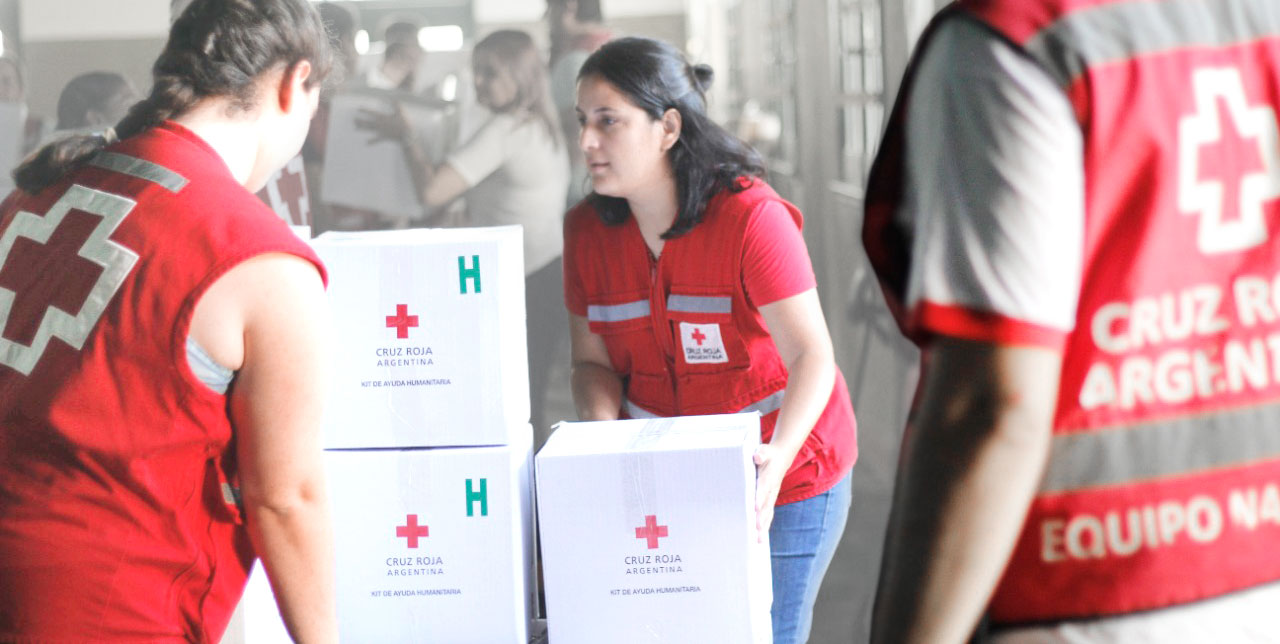 Voluntarios de la Cruz Roja Argentina entregando kits de ayuda humanitaria a instituciones.